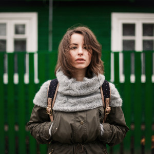 A girl in a backback staring off into space.